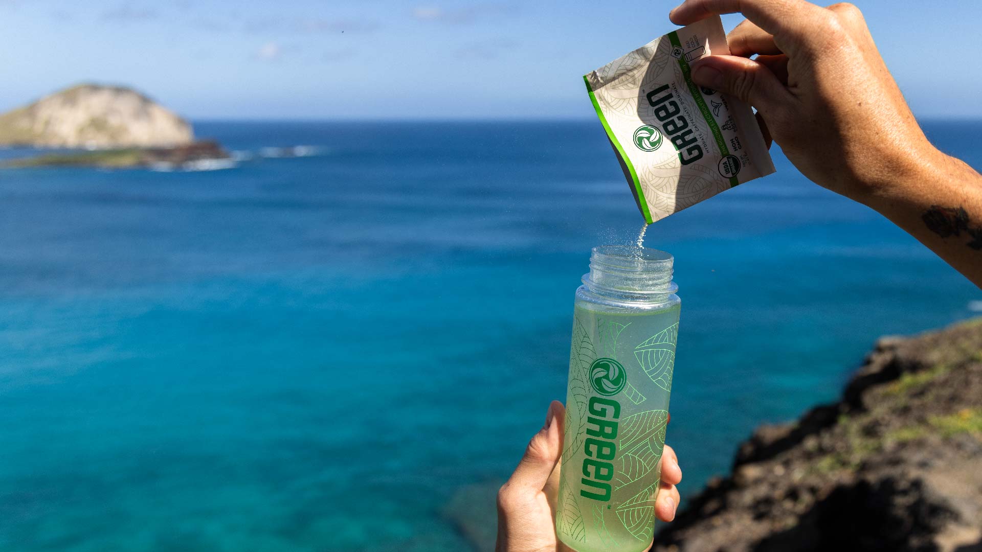 GREEN organic electrolyte sachet poured into a bottle by the ocean at Makapuu, Oahu