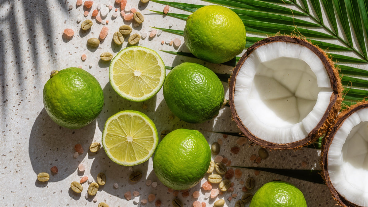Limes, split coconut, raw green coffee beans, and pink Himalayan salt on a stone counter